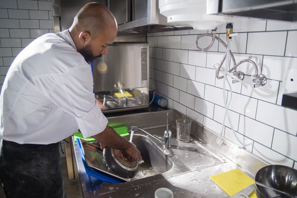 Washing kitchen utensils at a sink with a brush
